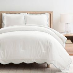 a bed with white sheets and pillows on top of it next to a night stand