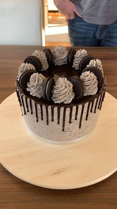 a chocolate cake with white frosting and oreo cookies on top, sitting on a plate