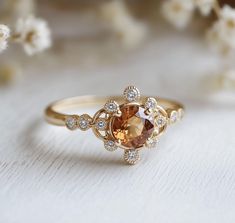 an orange and white diamond ring sitting on top of a table next to some flowers