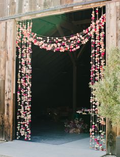 an open barn door decorated with pink flowers and greenery for a rustic wedding ceremony