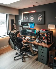 a man sitting at a desk in front of a computer monitor and sound mixing equipment