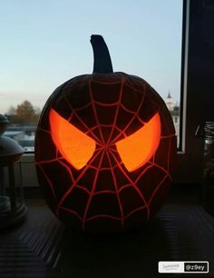 a spiderman pumpkin with glowing eyes is sitting on a window sill in front of a window