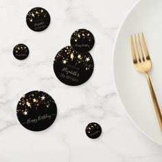 black and gold coasters with stars on them next to a plate, fork and knife