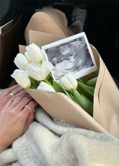 a bouquet of white tulips wrapped in a brown paper with a photo on it