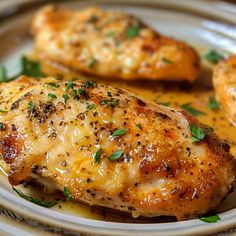 two pieces of chicken on a plate covered in sauce and garnished with parsley