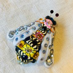 a close up of a brooch on a white cloth with beads and other things