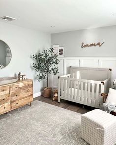 a baby's room with a white crib, dresser and mirror on the wall