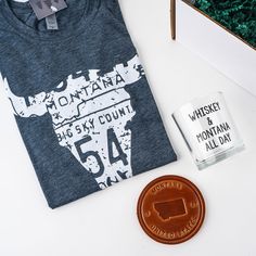 a bottle of whiskey next to a t - shirt with the word montana on it