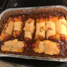 a pan filled with chili and cheese covered hot dogs