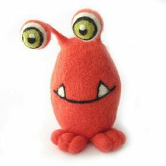 a red stuffed animal with big eyes sitting on a white surface