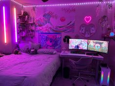 a bedroom with two computer monitors on top of a white desk next to a bed