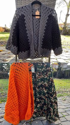 two crocheted sweaters on display in front of a basket