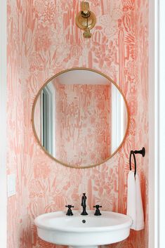 a white sink sitting under a mirror next to a wall mounted faucet in a bathroom