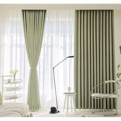 a bedroom with green curtains and white furniture