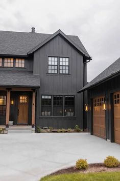 two garages in front of a large house with brown doors and windows on each side