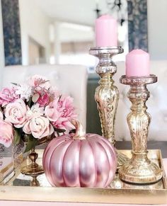 pink candlesticks are sitting on a tray next to flowers and other decor items