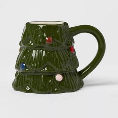 a green ceramic christmas tree mug with red, white and blue decorations on it's sides