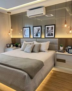 a bedroom with a bed, nightstands and pictures hanging on the wall above it