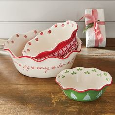 three christmas dishes sitting on top of a wooden table next to a wrapped present box