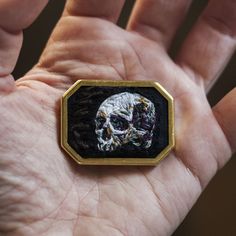 a person's hand holding a small patch with a skull on it