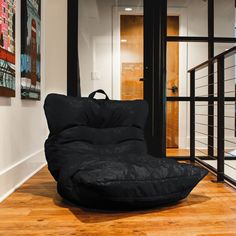 a black bean bag chair sitting on top of a hard wood floor next to a staircase