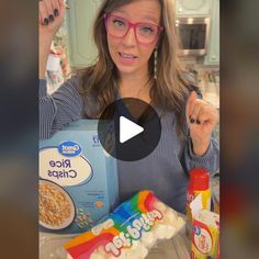 a woman in glasses is holding up some cereal and rice chips while pointing to the camera