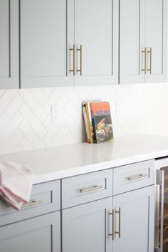 a kitchen with white cabinets and gold handles