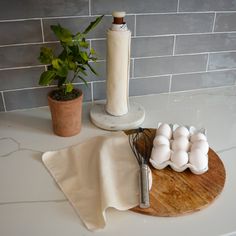 a wooden board topped with eggs next to a whisk and potted plant