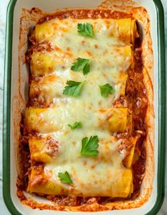 an enchilada casserole in a green dish with cheese and parsley