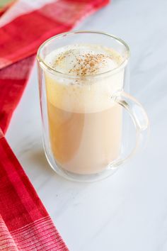 an eggnog latte in a glass mug with cinnamon sprinkles