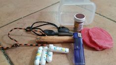 an assortment of crafting supplies sitting on a tile floor next to a plastic container