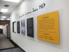 an office hallway with yellow and black signage on the wall, along with other information