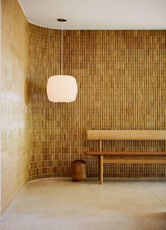 a wooden bench sitting next to a wall with a lamp hanging from it's side