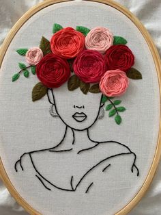 a woman's face with flowers in her hair is embroidered onto a piece of fabric