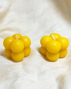 two yellow candles sitting on top of a white sheet