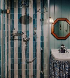 a bathroom with blue and white tiles on the walls, shower head, sink and mirror