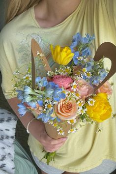 a woman holding a bouquet of flowers in her hands and scissors on the back of her chest