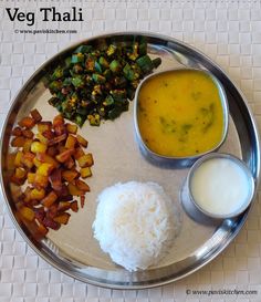 a silver plate topped with rice and vegetables next to two bowls of sauces on a table