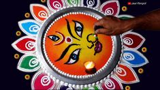 a person holding a lit candle in front of a decorated plate