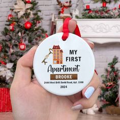 someone holding up a christmas ornament in front of a fireplace with the words, my first apartment broke