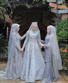 three women dressed in wedding attire standing next to each other