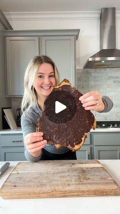 a woman holding up a large piece of chocolate cake in front of her face and smiling at the camera