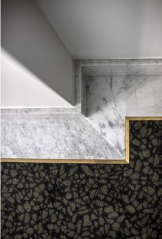 the corner of a room with marble walls and flooring in black and white colors