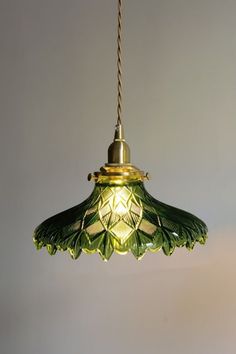 a green glass light hanging from a ceiling