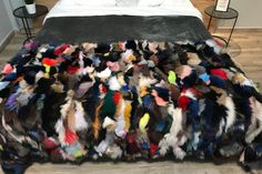 a bed covered in lots of colorful feathers on top of a hard wood floor next to a night stand