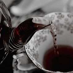 a person pours wine into a glass in front of a bowl filled with red liquid