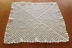 a white crocheted placemat sitting on top of a wooden table