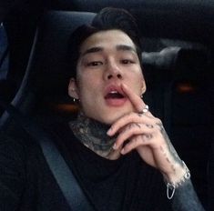 a man sitting in the back seat of a car with his finger on his lips