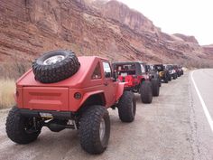 four jeeps are lined up on the side of the road