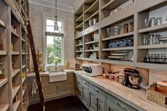 a kitchen with gray cabinets and shelves filled with dishes, coffee maker and other items